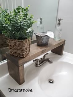 a bathroom sink with a wooden shelf above it and two plants on the counter top