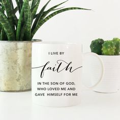 a white mug with the words faith on it next to a potted cactus and a plant