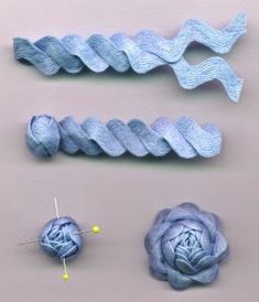 three pieces of blue yarn are next to each other on a gray surface with pins and needles