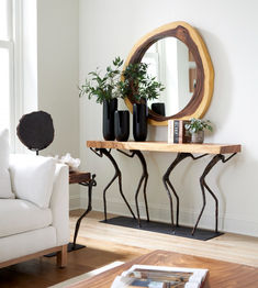 a living room with a white couch, mirror and planters on the side table