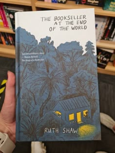 the book seller at the end of the world by ruth shaw is held up in front of a bookshelf