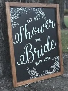 a chalkboard sign that says let us shower the bride with love next to a tree