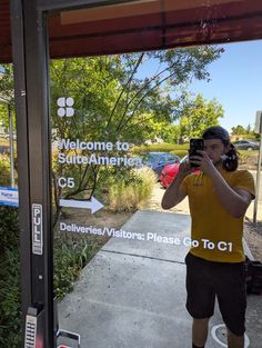 a man taking a selfie in front of a bus stop sign with the words welcome to sacramento written on it