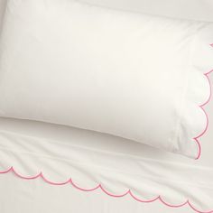 two white pillows with pink scalloped edges on top of each pillowcase in a bedroom