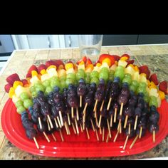 several skewers of fruit are arranged on a red platter