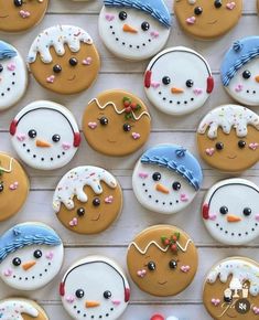 many decorated cookies are arranged in the shape of snowman and snowwoman faces on a white surface