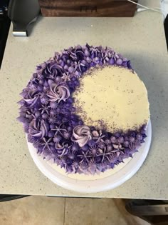 a cake decorated with purple flowers and sprinkles sits on a counter top