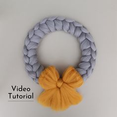 a yarn wreath with a yellow bow hanging from it's side on a white surface