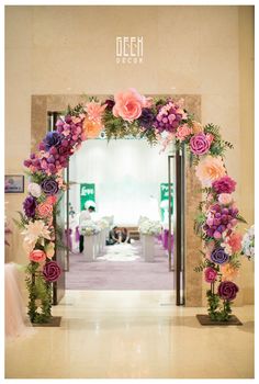 an archway decorated with flowers and greenery at the entrance to a wedding reception venue