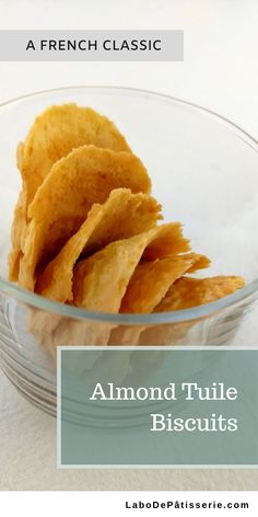 a glass bowl filled with potato chips on top of a white tablecloth and the words almond tulle biscuits