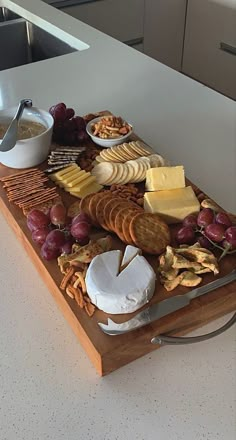 a platter with cheese, crackers and grapes is on the kitchen counter top