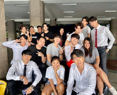 a group of people posing for a photo in front of a building with their hands up