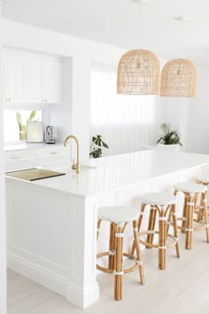 a kitchen with white walls and wooden stools in front of an island countertop