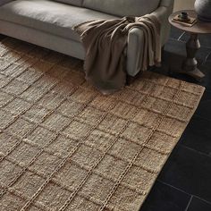 a living room with a gray couch and brown rug