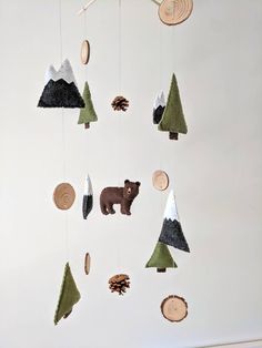 a mobile made out of wood and felt with trees, pinecones, and a bear