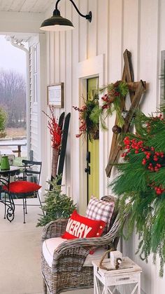 the front porch is decorated for christmas with evergreen and red berries on the wreaths