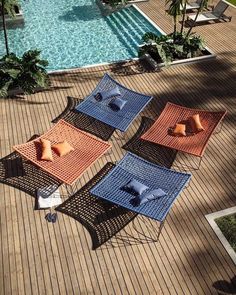 four different colored chairs sitting on top of a wooden floor next to a swimming pool