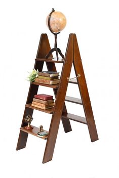 a wooden ladder with books on top and a globe sitting on top of the shelf