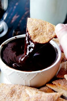 a person dipping some kind of chocolate in a bowl with crackers on the side