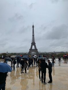 many people with umbrellas standing in front of the eiffel tower