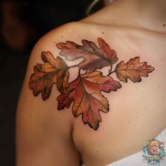 a woman's shoulder with an orange and red leaf tattoo on her left shoulder