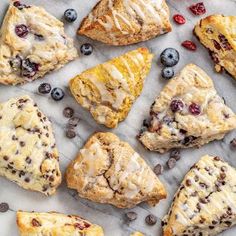 blueberry scones and other pastries are arranged on a sheet of parchment paper