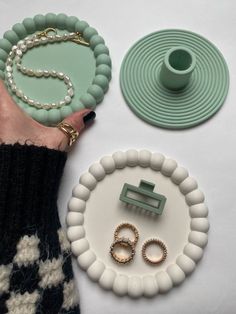 a person's hand with rings, bracelets and other items on a table