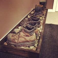 several pairs of shoes are lined up in a drawer on the ground next to a wall