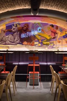 the interior of a restaurant with colorful murals on the ceiling and wooden chairs around tables