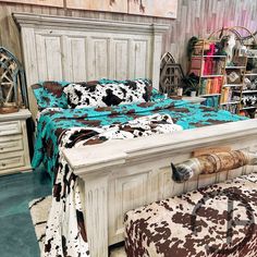 the bed is made up with cow print blankets and pillows on it's headboard