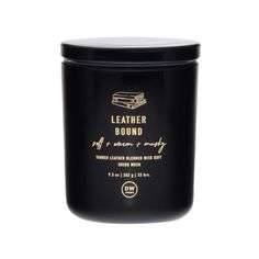 a black candle that is sitting on a white surface with the words leather bound written in gold