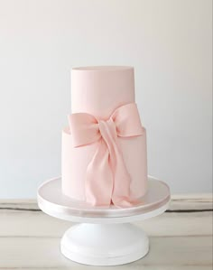 a three tiered pink cake with a bow on top