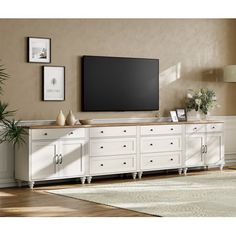 a living room with a large flat screen tv on top of a white entertainment center