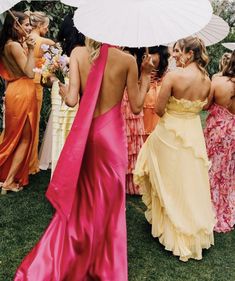 a group of women standing around each other holding umbrellas in their hands and wearing dresses