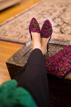 a woman's feet in high heels sitting on top of a trunk