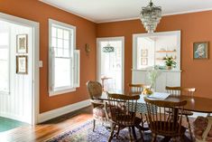 a dining room with orange walls and white trim on the doors, windows, and rugs