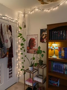 a living room with bookshelves, plants and pictures on the wall above them