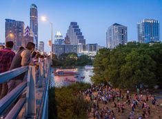 people are standing on the edge of a bridge overlooking a river and cityscape