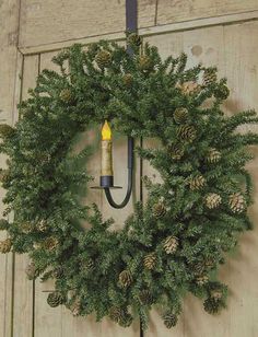 a wreath hanging on the side of a door with a lit candle in front of it