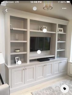 a living room with white bookcases and a flat screen tv