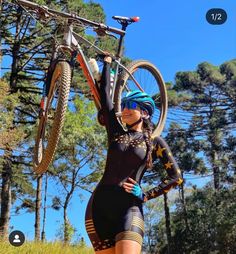 a woman is holding her bike up in the air