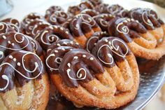 there are many donuts with chocolate icing on the top and bottom, sitting on a silver platter