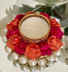 a candle surrounded by pearls and flowers on a table