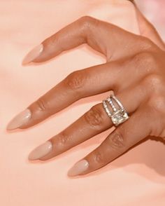 a close up of a person's hand with an engagement ring on her finger