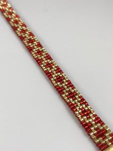 a gold and red bracelet on a white surface