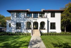 a large white house sitting on top of a lush green field