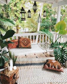 a porch with lots of plants and pillows on it