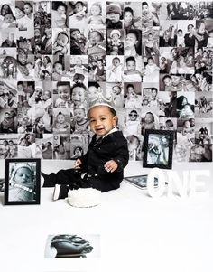 a little boy sitting on top of a table in front of a wall with pictures