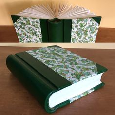 an open book sitting on top of a wooden table next to a green and white cover