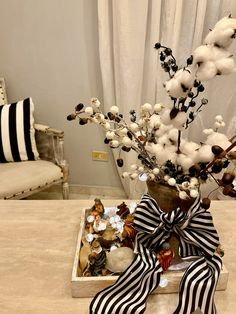 a vase filled with cotton flowers on top of a table next to a pair of shoes